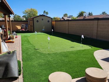 A Sunny backyard putting green with an artificial turf installation by Tempe Turf Installers.