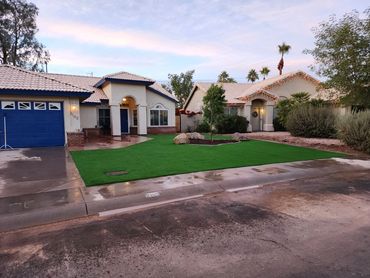 Twilight view of a house with a front yard of an artificial grass installation by Tempe Turf Install
