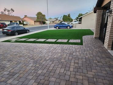 A driveway with pavers leading to an artificial turf installation by Tempe Turf Installers.