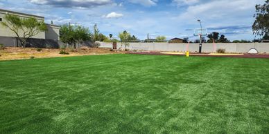Wide open field of artificial grass with bue skies and clouds