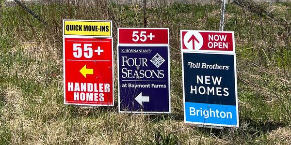Signs advertising 55+ housing communities and new homes.