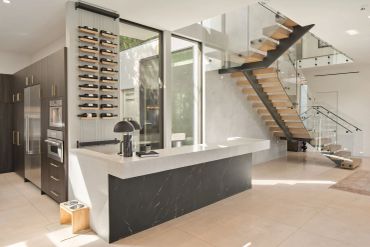 Modern kitchen with floating wooden stairs and wine rack.