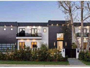 Modern two-story house with black and white facade and large windows.