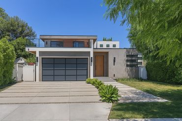 Modern two-story house with sleek design and large garage door.