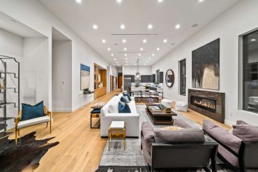 Modern open-concept living room and kitchen with stylish furniture and fireplace.