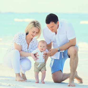 Happy family with baby on the beach, enjoying a sunny day.