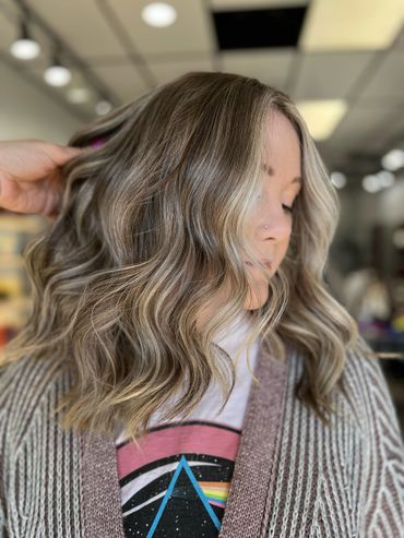 Woman with wavy, ash blonde hair and a side nose piercing.