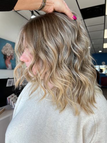 Side profile of a woman with wavy, highlighted blonde hair.