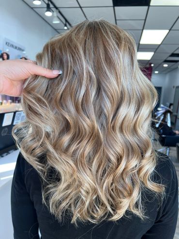 Wavy blonde hair with highlights styled in a salon.
