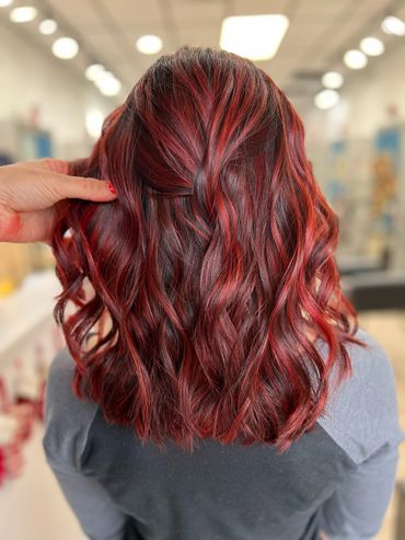 Wavy hair dyed in vibrant red hues with subtle highlights.