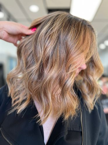 Wavy, highlighted shoulder-length hair styled in soft curls.