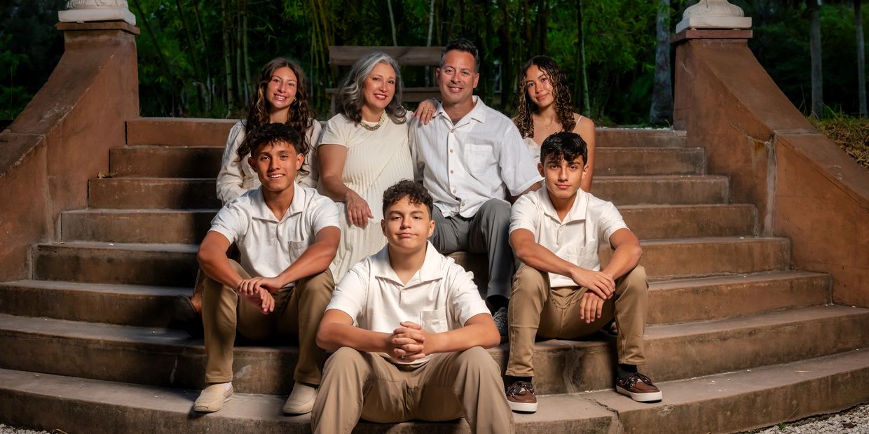 A family of seven posing together on outdoor stairs at night.