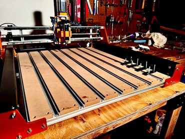 A CNC machine on a wooden workbench in a workshop.