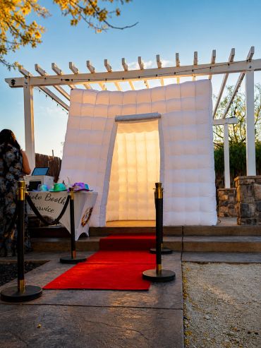 Inflatable photo booth with red carpet setup outdoors.