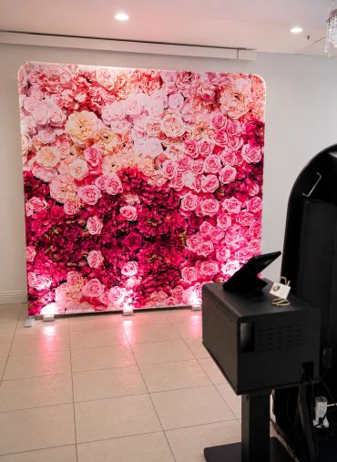 Photo booth setup with floral printed backdrop and mirror booth