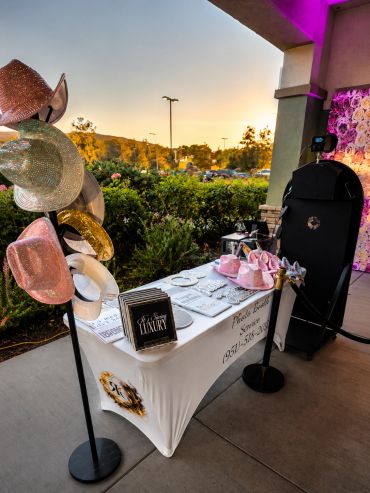 Outdoor photo booth setup with sparkly hats and props at sunset.