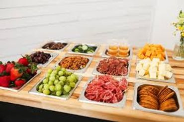 A table with assorted fruits, nuts, cheese, and crackers arranged in trays.