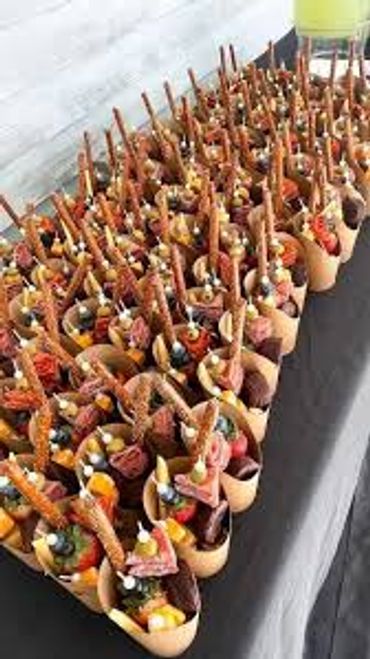 Rows of gourmet snack cones filled with cured meats and pretzels.