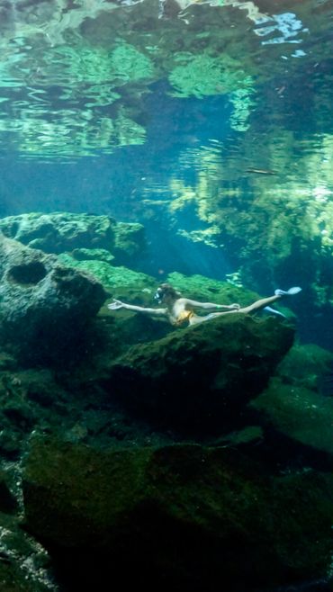 Ilustración mujer haciendo snorkel en cenote abierto.