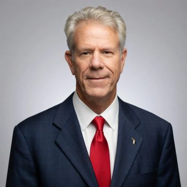 Portrait of an older man in a suit with a red tie.