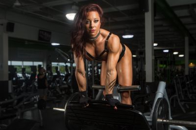 A muscular woman working out in a gym, focused on strength training.