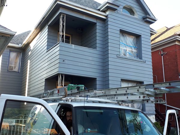 House exterior mid-renovation with taped windows and a work van parked out front.