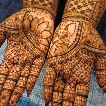 Intricate mehndi designs featuring a sunflower and a dog on palms.