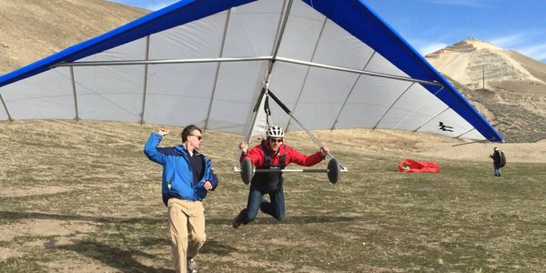An instructor guides a hang gliding student in for a soft landing at the point of the mountain near Salt Lake City Utah