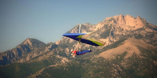 A hang glider with lone peak in the background
