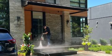 A Blast Away employee power washing the front porch of a residential house.