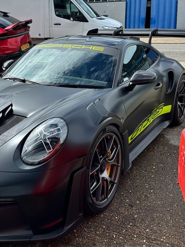 Matte black Porsche 911 GT3 RS with neon yellow accents and aggressive aerodynamics.