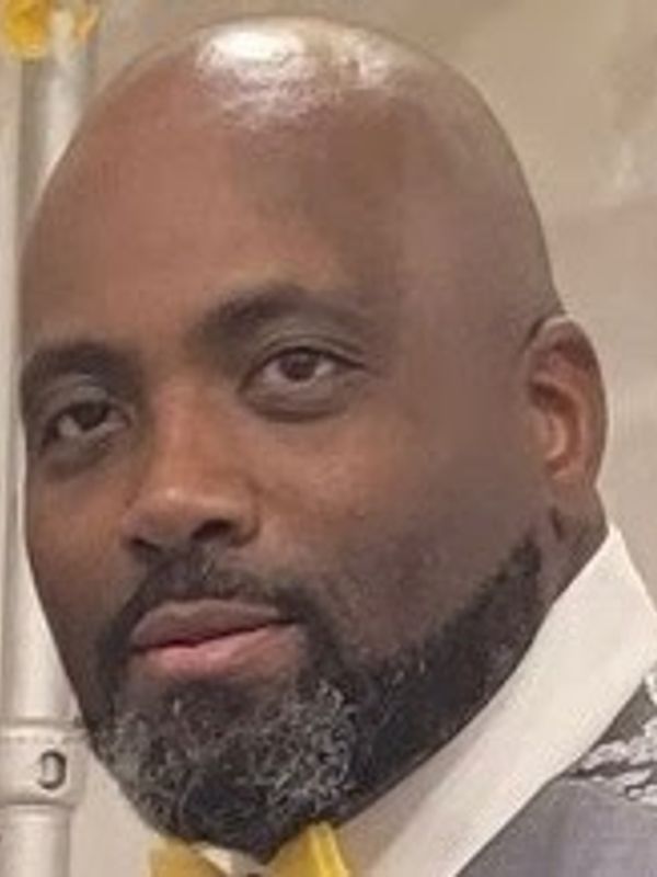 Close-up portrait of a bald man with a beard wearing a yellow bow tie.