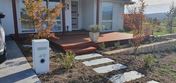 Front entry deck with sandstone retaining wall, steppers and complimentory planting