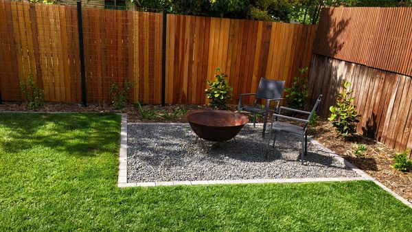 Gravel firepit area with lawn and garden beds surrounding