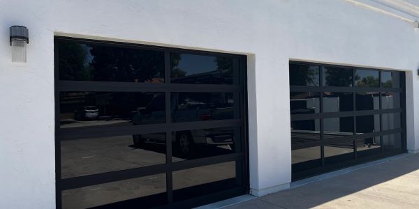 Modern black glass garage doors on a white building.