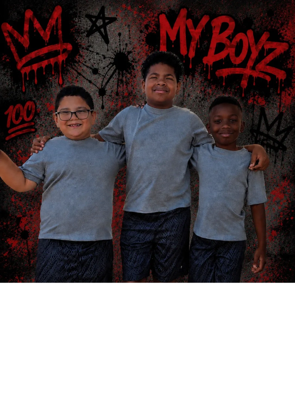 Three boys posing with arms around each other in front of graffiti.