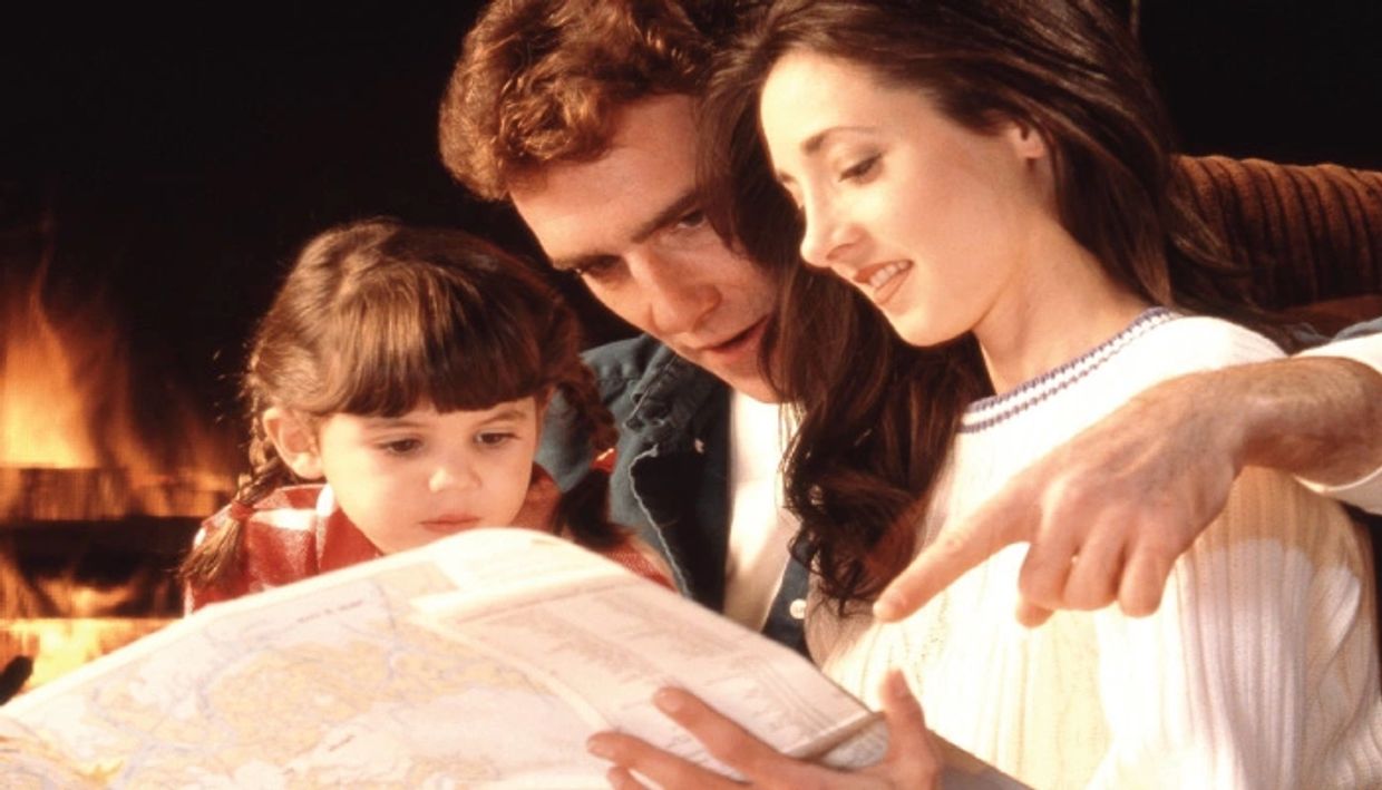 Family reading a map together by the fireplace.