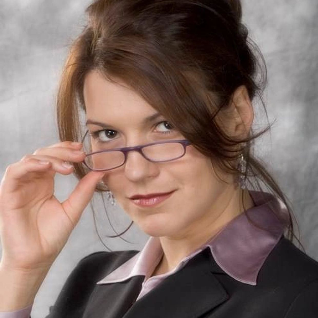 Confident woman adjusting her glasses with a slight smile.