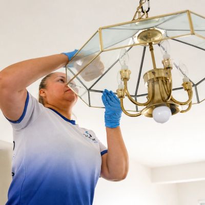 Person cleaning a chandelier wearing blue gloves.