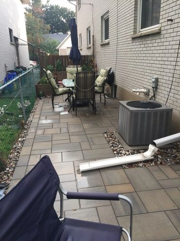 A backyard patio with outdoor furniture and an air conditioning unit.