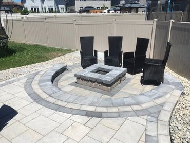 Backyard patio with fire pit and black wicker chairs.