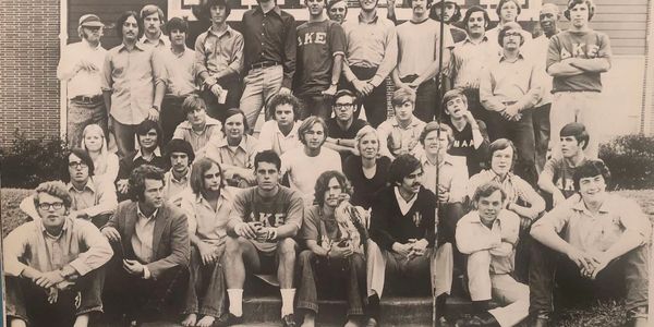 Black and white group photo of young adults posing outside a building.
