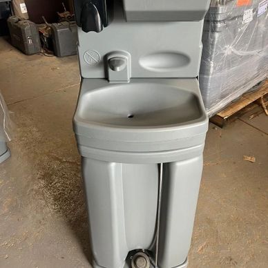 A portable gray handwashing station with soap dispenser in a warehouse.