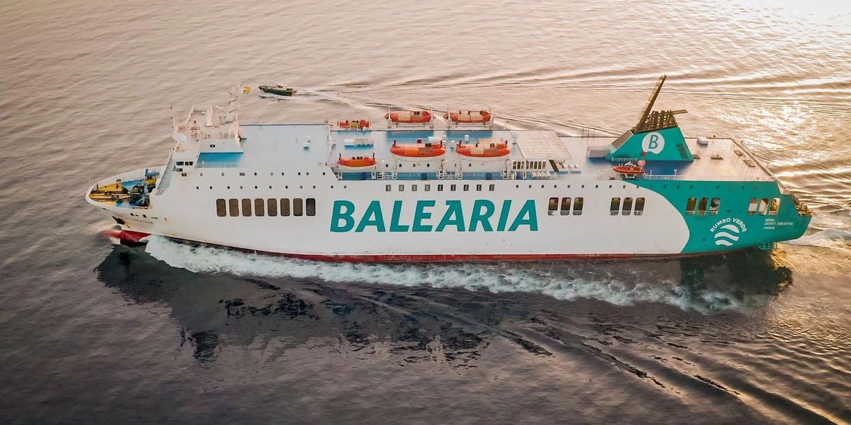 A large Balearia ferry cruising on calm waters during sunset.
