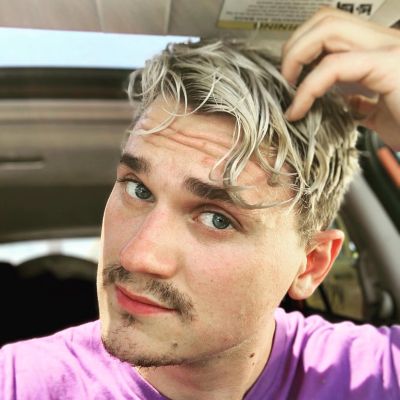 Young man with blond hair taking a selfie in a car.
