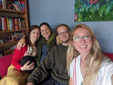 Four friends smiling together on a couch.