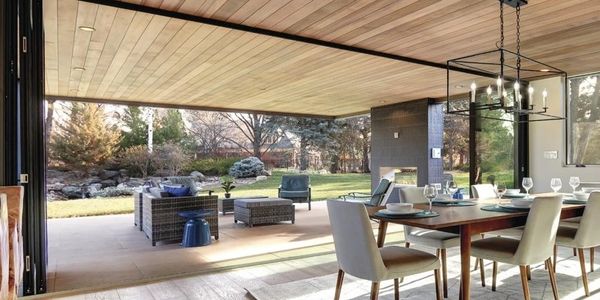 Spacious outdoor patio with modern seating and dining area overlooking a lush garden.