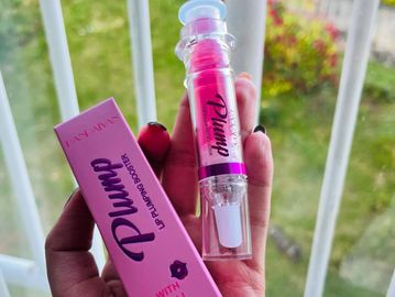 Hand holding a pink lip plumping booster with chili extract.