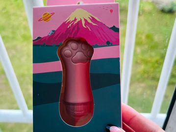 Hand holding a paw-shaped object in colorful packaging.