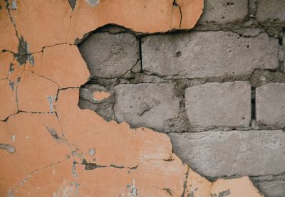 Cracked plaster revealing bricks underneath.